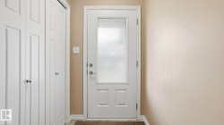 Entryway featuring a white paneled door with frosted glass, brushed nickel hardware, and neutral wall paint - 