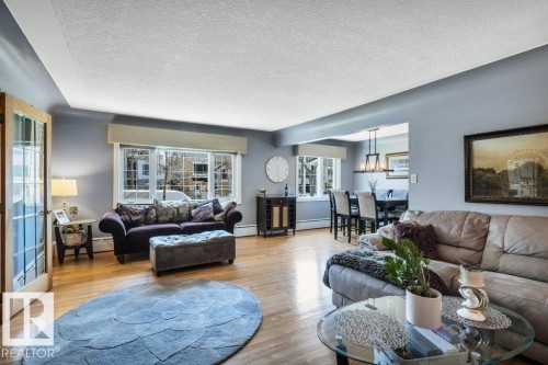 Spacious living area featuring wood-finish flooring, ample natural light from large windows, and a clear entryway with French doors - 10616 136 Street, Edmonton, AB - Indoor Photo Showing Living Room