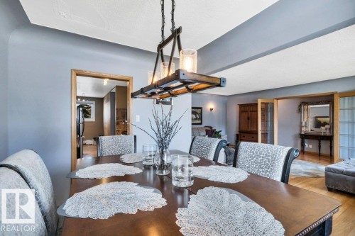 Dining area with a wood-finish table, distinct chandelier lighting, and light gray walls - 10616 136 Street, Edmonton, AB - Indoor Photo Showing Dining Room