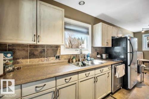 Kitchen featuring light-toned cabinetry, a double basin stainless steel sink, and a tiled backsplash - 10616 136 Street, Edmonton, AB - Indoor Photo Showing Kitchen With Double Sink