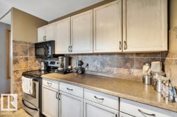 Kitchen featuring distressed white cabinetry, stone-look tile backsplash, dark countertops, built-in microwave, and stainless steel appliances - 