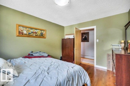 Hardwood flooring throughout, with light green wall paint and white trim - 10616 136 Street, Edmonton, AB - Indoor Photo Showing Bedroom