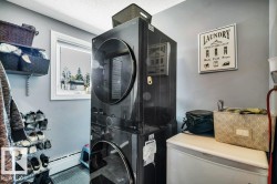 Dedicated utility space featuring a stacked black washer and dryer unit, a single window, and light grey wall paint - 
