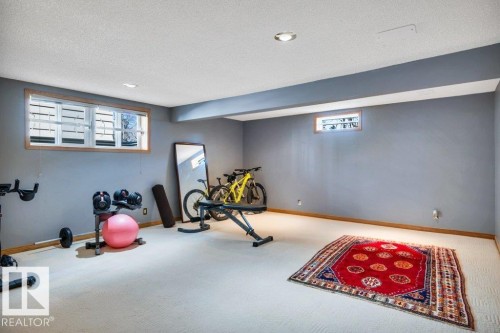 Finished basement area featuring recessed lighting, a large egress window with white blinds, and a smaller horizontal window - 10616 136 Street, Edmonton, AB - Indoor Photo Showing Gym Room