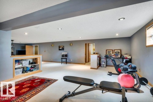 Spacious lower-level area featuring recessed lighting, light-colored carpeting, a built-in wooden bar with storage, and neutral gray walls - 10616 136 Street, Edmonton, AB - Indoor Photo Showing Other Room