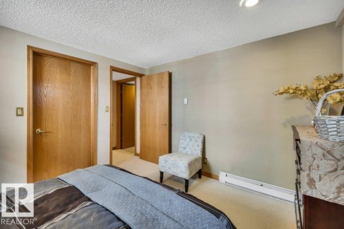 Bedroom featuring light neutral wall paint, wood-finish interior doors, textured ceiling, and neutral-toned carpet flooring - 10616 136 Street, Edmonton, AB - Indoor Photo Showing Bedroom