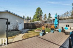 Expansive outdoor deck featuring composite decking, a frosted privacy screen, and direct access to a fenced yard with a fire pit and mature trees - 