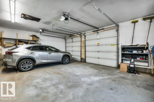 Two-car garage featuring concrete flooring, segmented garage doors, and overhead track lighting - 10616 136 Street, Edmonton, AB - Indoor Photo Showing Garage