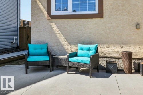 Concrete patio with a textured stucco exterior and a white-framed window - 10616 136 Street, Edmonton, AB - Outdoor With Deck Patio Veranda With Exterior