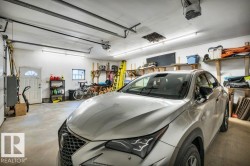 Spacious two-car garage featuring a concrete floor, white painted walls, and overhead fluorescent lighting - 