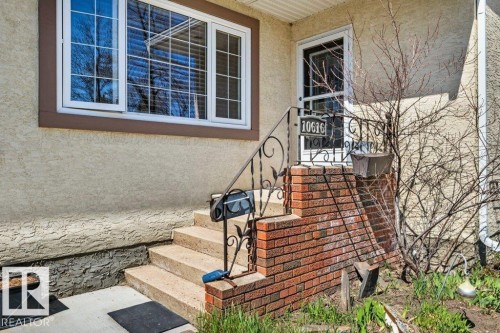 Front entry featuring concrete steps, brick foundation detailing, and an ornamental metal handrail - 10616 136 Street, Edmonton, AB - Outdoor