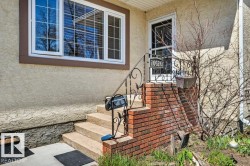 Front entry featuring concrete steps, brick foundation detailing, and an ornamental metal handrail - 