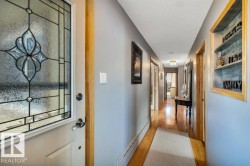 Entryway featuring a front door with leaded glass insert, wood-finish flooring, light gray wall paint, and recessed wall shelving with a textured back panel - 