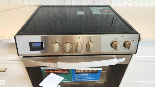 Stainless steel range with a black glass cooktop and digital controls, integrated into a countertop with a subway tile backsplash - 603 9028 Jasper Avenue, Edmonton, AB - Indoor
