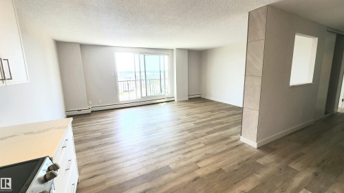 Open-concept living area with wood-finish flooring, a neutral color palette, and sliding glass doors to the exterior - 603 9028 Jasper Avenue, Edmonton, AB - Indoor Photo Showing Other Room