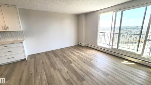Spacious open-concept room featuring wide plank wood-finish flooring and a full wall of sliding glass doors - 603 9028 Jasper Avenue, Edmonton, AB - Indoor
