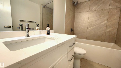 White vanity with integrated rectangular sink and polished chrome faucet - 603 9028 Jasper Avenue, Edmonton, AB - Indoor Photo Showing Bathroom