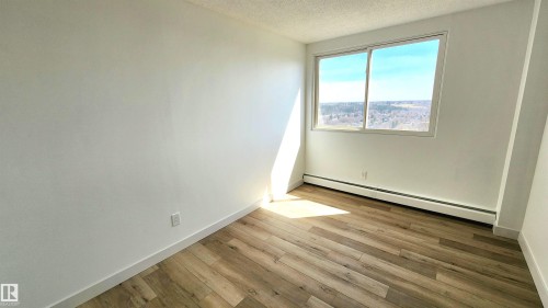 Bright room featuring wood-finish flooring, white baseboards, and a large window - 603 9028 Jasper Avenue, Edmonton, AB - Indoor Photo Showing Other Room