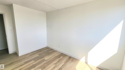 Room featuring light wood-finish flooring, white baseboards, and neutral wall tones - 603 9028 Jasper Avenue, Edmonton, AB - Indoor Photo Showing Other Room