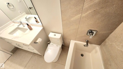 Bathroom featuring a white vanity with an integrated sink, polished chrome faucet, and a large wall-mounted mirror - 603 9028 Jasper Avenue, Edmonton, AB - Indoor Photo Showing Bathroom