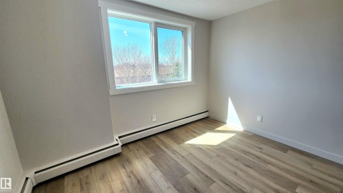 Bright room featuring wood-finish flooring, white baseboards, and a large window with white trim - 603 9028 Jasper Avenue, Edmonton, AB - Indoor Photo Showing Other Room