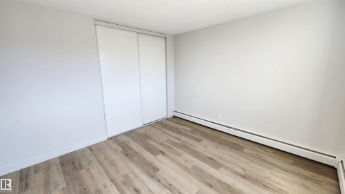 Room featuring wood-finish flooring, white baseboards, and light gray painted walls - 603 9028 Jasper Avenue, Edmonton, AB - Indoor Photo Showing Other Room