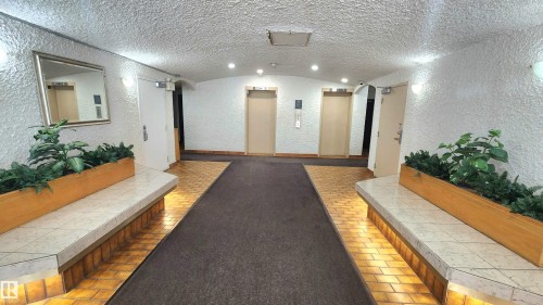 Hallway featuring textured white walls, recessed ceiling lighting, and a dark carpet runner - 603 9028 Jasper Avenue, Edmonton, AB - Indoor Photo Showing Other Room