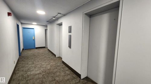 Carpeted hallway featuring recessed lighting and a bright blue entry door - 603 9028 Jasper Avenue, Edmonton, AB - Indoor Photo Showing Other Room