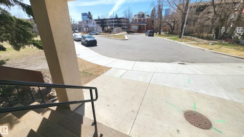 Concrete exterior stairs with a black metal handrail leading to a paved walkway - 603 9028 Jasper Avenue, Edmonton, AB - Outdoor