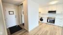 Modern kitchen featuring light wood-finish flooring, white cabinetry, and stainless steel appliances - 603 9028 Jasper Avenue, Edmonton, AB  - Indoor 
