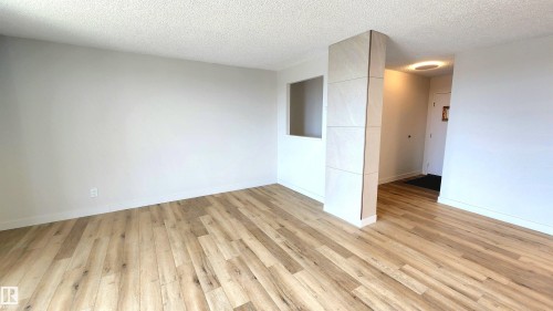 Open-concept living area featuring light wood-finish flooring, white baseboards, and neutral wall tones - 603 9028 Jasper Avenue, Edmonton, AB - Indoor Photo Showing Other Room