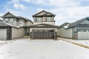 The property features a two-story exterior with light-colored siding, dark trim, and stone accents - 97 Dansereau Way, Beaumont, AB  - Outdoor With Facade 
