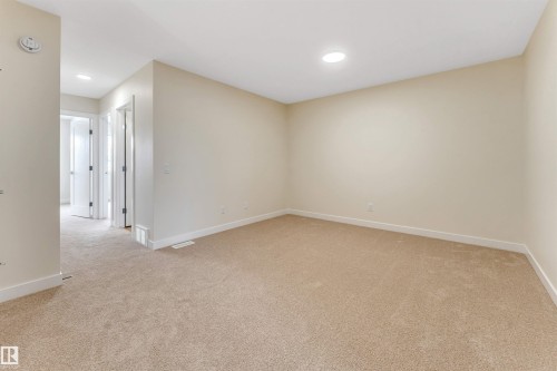 This room features neutral-toned carpet flooring and light-colored walls, creating a versatile space - 97 Dansereau Way, Beaumont, AB - Indoor Photo Showing Other Room