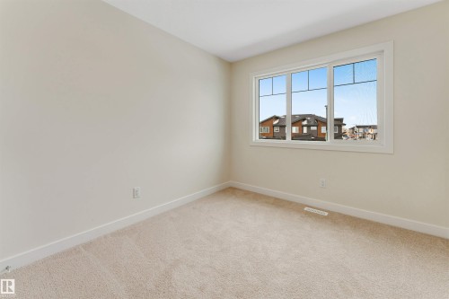 This room features beige carpeting and light-colored walls, complemented by a white-trimmed window - 97 Dansereau Way, Beaumont, AB - Indoor Photo Showing Other Room