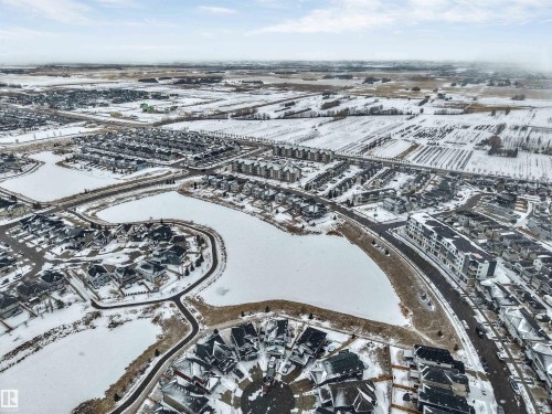 Aerial view of the community, featuring residential properties, roads, and a frozen body of water - 97 Dansereau Way, Beaumont, AB - Outdoor With View