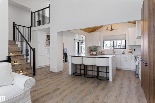 Open-concept kitchen featuring white cabinetry, a central island with countertop seating, and a large window - 38 Woodcrest Avenue, St. Albert, AB - Indoor Photo Showing Other Room