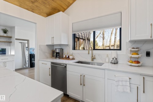 Modern kitchen featuring white cabinetry, light-toned countertops with veining, and a stainless steel under-mount sink with a gold-tone faucet - 38 Woodcrest Avenue, St. Albert, AB - Indoor Photo Showing Kitchen