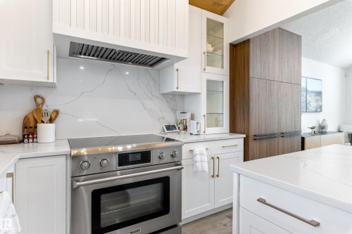 Sleek kitchen featuring a stainless steel range, white shaker cabinetry with gold-tone hardware, and an expansive island - 38 Woodcrest Avenue, St. Albert, AB - Indoor Photo Showing Kitchen