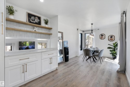 Dining area featuring wood-finish flooring, a contemporary chandelier, and a bay window - 38 Woodcrest Avenue, St. Albert, AB - Indoor