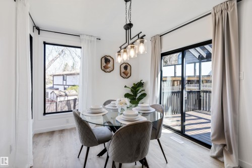 Dining area featuring light wood-finish flooring, a contemporary linear chandelier with glass shades, and white walls - 38 Woodcrest Avenue, St. Albert, AB - Indoor Photo Showing Dining Room
