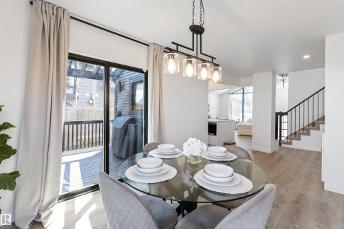 Dining area featuring a contemporary linear chandelier with clear glass shades, light wood-finish flooring, and a sliding glass door leading to an outdoor deck - 38 Woodcrest Avenue, St. Albert, AB - Indoor Photo Showing Dining Room