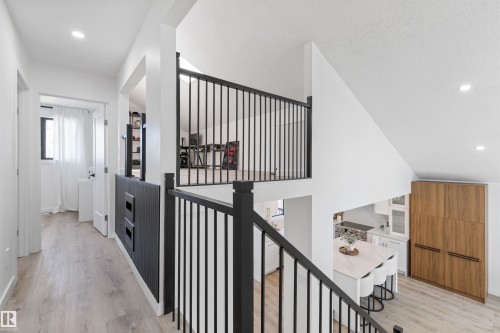 Loft area featuring sleek black railings, light wood-finish flooring, recessed lighting, and a partial open concept to the kitchen below - 38 Woodcrest Avenue, St. Albert, AB - Indoor Photo Showing Other Room