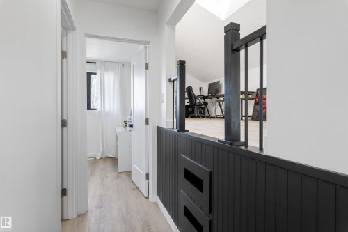 Hallway with light wood-finish flooring, white walls, and a black wainscoting and railing - 38 Woodcrest Avenue, St. Albert, AB - Indoor Photo Showing Other Room