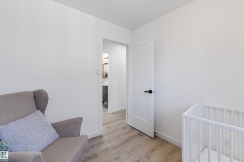 Interior room featuring light wood-finish flooring and a white paneled door with black hardware - 38 Woodcrest Avenue, St. Albert, AB - Indoor Photo Showing Other Room