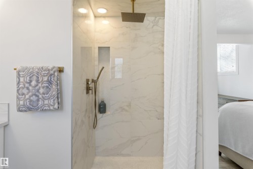 Walk-in shower featuring large format tile, a built-in shower niche, recessed lighting, and a gold-tone rain showerhead with a handheld sprayer - 38 Woodcrest Avenue, St. Albert, AB - Indoor Photo Showing Bathroom