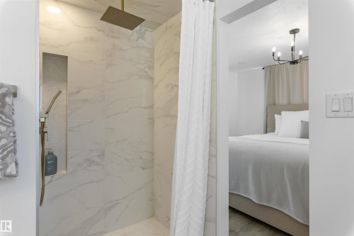 Walk-in shower featuring large format veined wall tiles, a built-in shower niche, and a gold-tone rain shower head - 38 Woodcrest Avenue, St. Albert, AB - Indoor Photo Showing Bathroom