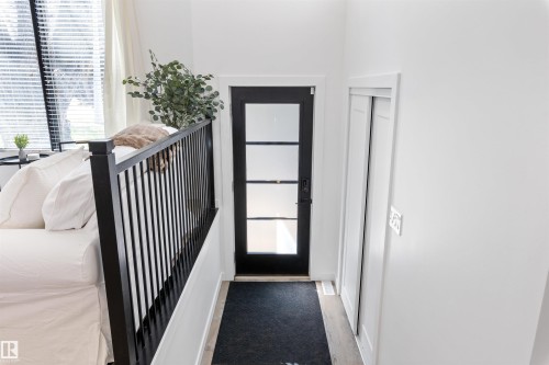 Entryway featuring a contemporary black door with multiple clear glass panels, light wood-finish flooring, and white walls - 38 Woodcrest Avenue, St. Albert, AB - Indoor Photo Showing Other Room