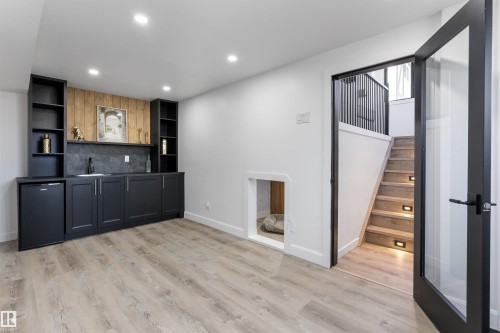 Lower level featuring wood-finish flooring, recessed lighting, and a built-in wet bar with dark cabinetry and a beverage refrigerator - 38 Woodcrest Avenue, St. Albert, AB - Indoor