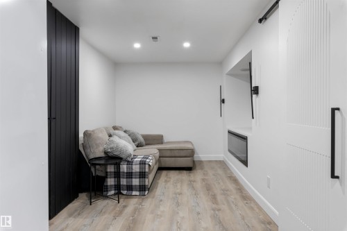Bright interior space featuring recessed lighting, wood-finish flooring, a built-in electric fireplace, and a sliding barn door with vertical paneling - 38 Woodcrest Avenue, St. Albert, AB - Indoor