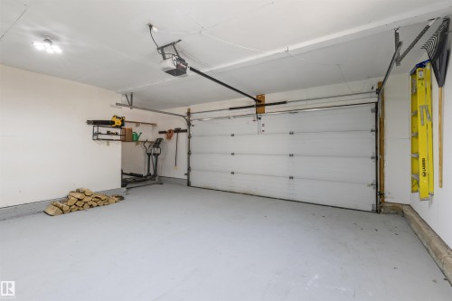 Spacious garage with a light gray painted floor, white walls, and an automatic garage door opener - 38 Woodcrest Avenue, St. Albert, AB - Indoor Photo Showing Garage